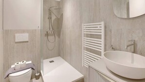 A modern bathroom with a freestanding bathtub, a large mirror, and a white sink. - Studio climatisé lumineux et cosy (Neuilly-sur-Seine)