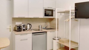 A compact kitchenette with a microwave, toaster, kettle, and sink. - Air-conditioned studio offering comfort and elegance (Neuilly-sur-Seine)