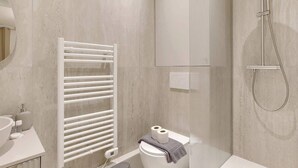 A modern bathroom with a white toilet, a towel rack, a shower, and a mirror. - Air-conditioned studio offering comfort and elegance (Neuilly-sur-Seine)