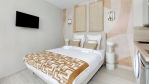Habitación de hotel con cama, televisión montada en la pared y lavadora.