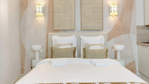 Una habitación de hotel moderna con una cama grande, dos lámparas de pared y un panel decorativo.