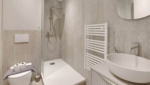 A modern bathroom with a freestanding bathtub, a large mirror, and a white towel rack. - Studio climatisé confort & charme – Neuilly (Neuilly-sur-Seine)