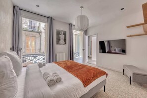 Ein modernes Hotelzimmer mit einem großen Bett, einem Fernseher, einem Balkon mit Blick und einem Bild an der Wand.