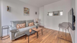 Un salon moderne avec un canapé gris, une petite table, un fauteuil et un plancher en bois.