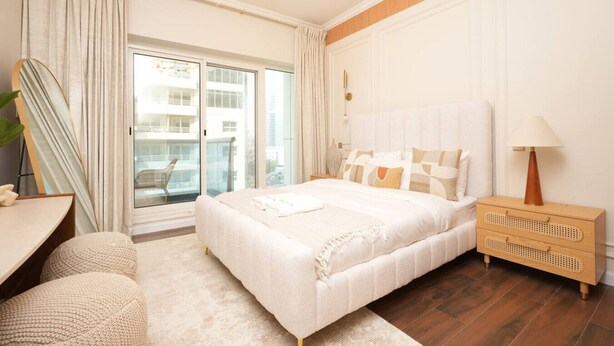 Una camera moderna con un letto grande, un comodino, una lampada e vista all'esterno tramite una porta scorrevole.