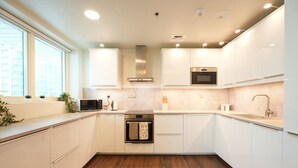 Una cucina moderna con mobili bianchi, forno integrato, microonde e cappa aspirante in acciaio inossidabile.