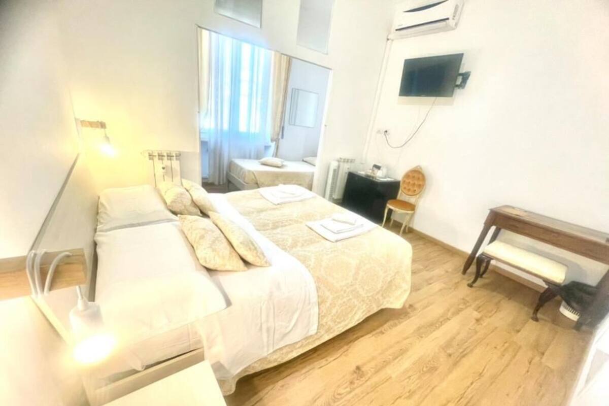 A hotel room with two beds, a television, a piano, and a window with curtains.