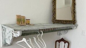 A rustic wooden shelf with hanging clothes and a mirror.