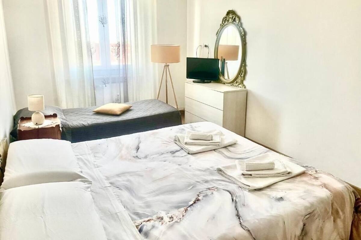 A hotel room with two beds, a television, a mirror, and a lamp.
