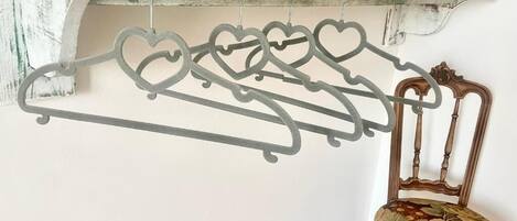 A chair with a floral cushion and a metal coat rack with heart-shaped hangers.