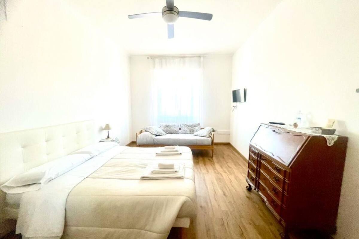 A hotel room with two beds, a ceiling fan, a dresser, and a television.