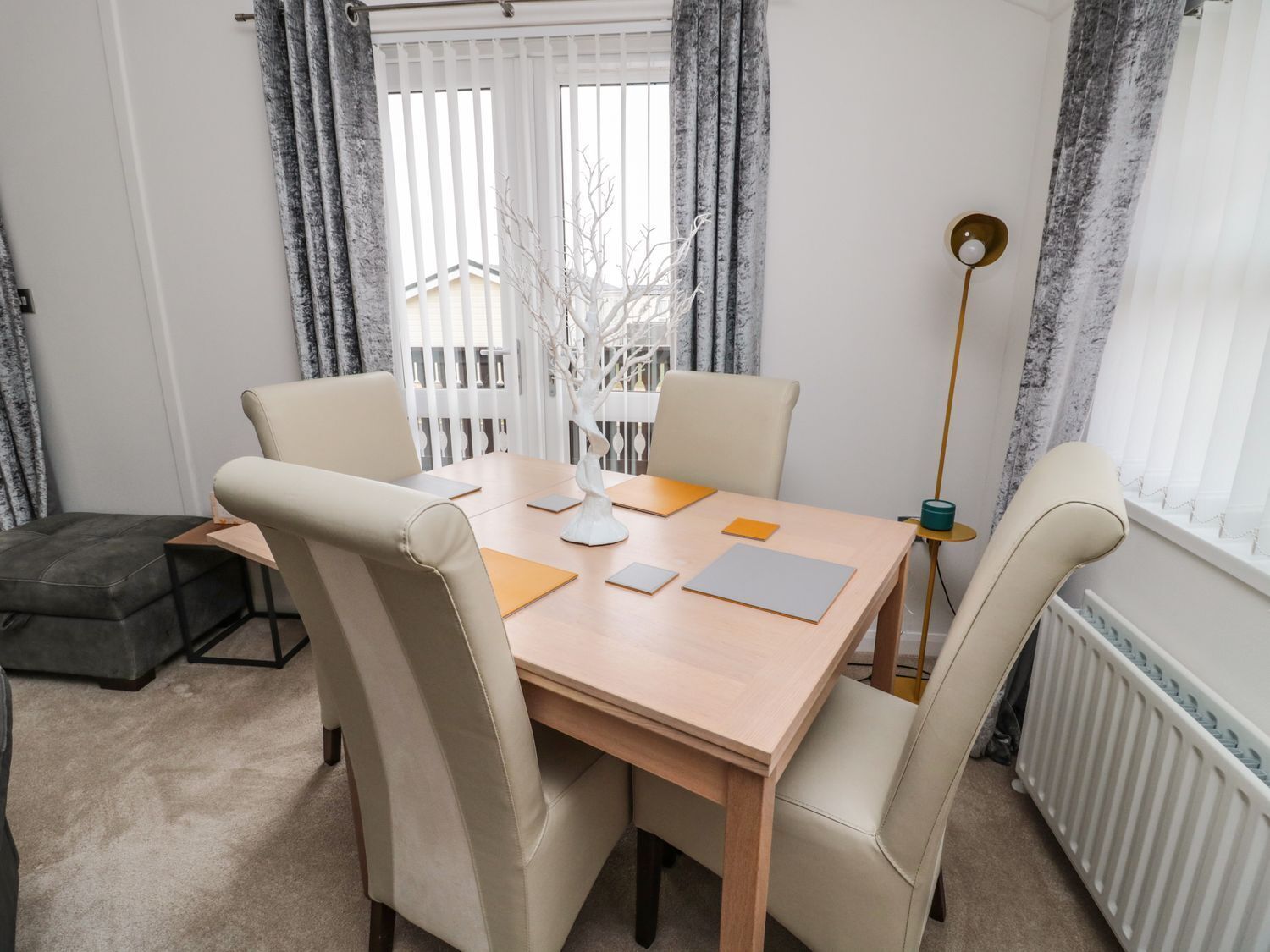 Een eethoek met een houten tafel, vier stoelen en een decoratieve boom.