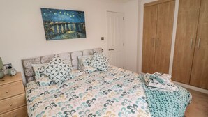 Une chambre à coucher avec un lit, une table de chevet, une armoire et un tableau au mur.
