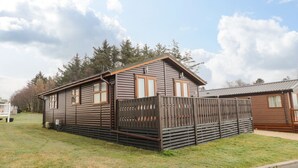 Une cabane en bois avec une cour clôturée, un petit porche et un ciel dégagé.