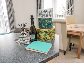 A room with a desk, a bottle of wine, a notebook, and a decorative lamp with a jungle theme. - Nevaeh Lodge (Morpeth)