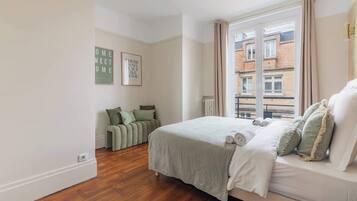 Una camera da letto con un letto, una finestra e un divano verde.