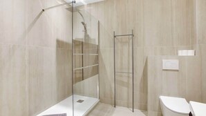 A modern bathroom with a glass shower enclosure, a white toilet, and a towel on the floor. - Elegant T2 in Neuilly-sur-Seine – Quiet & Comfortable (Neuilly-sur-Seine)