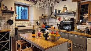 Ett modernt kök med en köksö i trä, rostfria köksmaskiner och ett stort utbud av köksredskap.
