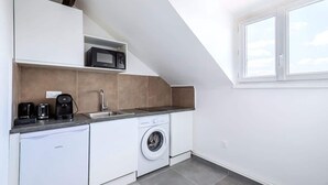 A compact kitchen with a washing machine, a microwave, and a coffee maker. - Studio fonctionnel et calme au cœur d'Issy (Issy-les-Moulineaux)