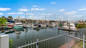 A marina with multiple boats docked, a clear sky, and a metal railing in the foreground. - Zen Dockside Point Marina View - Patio - Parking (Darwin)