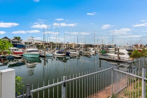 A marina with multiple boats docked, a clear sky, and a metal railing in the foreground. - Zen Dockside Point Marina View - Patio - Parking (Darwin)