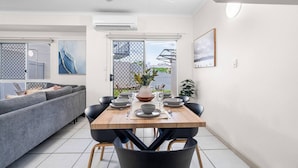 A modern dining area with a wooden table set for four, surrounded by black chairs. - Zen Dockside Point Marina View - Patio - Parking (Darwin)