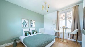 A modern bedroom with a large bed, a small round table, and two chairs. - Studio Chic & Cosy au Cœur d'Issy (Issy-les-Moulineaux)