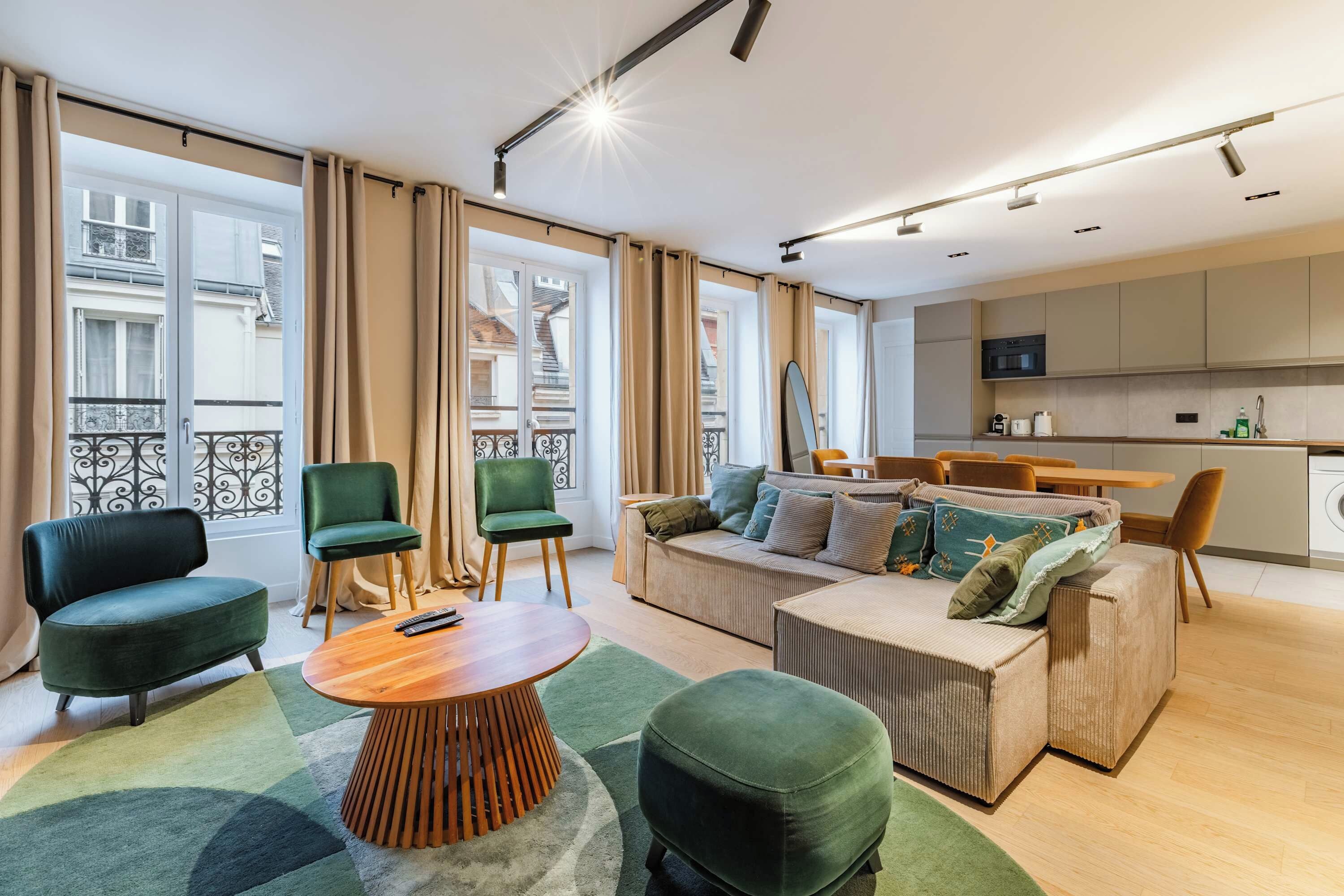 A modern living room with a sofa, chairs, a coffee table, and a kitchen area with appliances.