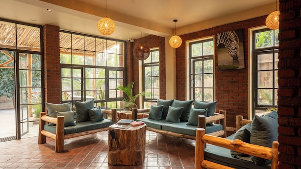 A spacious indoor area with brick walls, large windows, and wooden furniture. - ZONDELA HOUSE (Arusha)