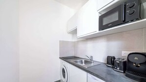 Una cucina funzionale con lavatrice, forno a microonde, tostapane e macchina da caffè.