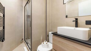 A modern bathroom with a glass shower enclosure, a white toilet, and a large rectangular sink with a black countertop. - Studio Lumineux au Cœur de Paris Centre (Paris)