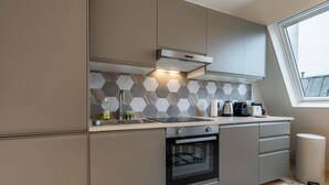 A modern kitchen with a built-in oven, a stainless steel range hood, and a window providing natural light. - Cocon pour 2 personnes central - Beaubourg / Notre-Dame (Paris)