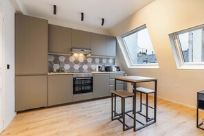 Eine moderne Küche mit Einbauofen, einem kleinen Esstisch und einem Fenster mit Blick auf die Stadt.