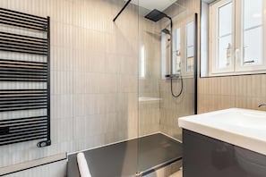 A modern bathroom with a glass shower enclosure, a black towel rack, and a large mirror. - Cocon pour 2 personnes central - Beaubourg / Notre-Dame (Paris)
