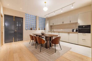 A modern kitchen with a central island, light-colored cabinets, and a black refrigerator. - Grand 4 pièces climatisé avec patio à Paris (Paris)