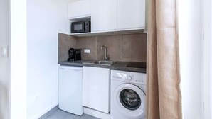 A compact kitchen with a washing machine, a microwave, and a coffee maker. - Studio chaleureux au coeur de ville Issy (Issy-les-Moulineaux)