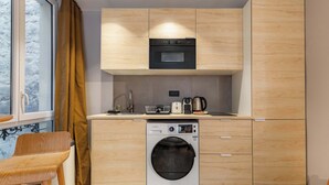 Une cuisine compacte équipée d’un lave-linge, d’un four à micro-ondes et d’une machine à café.