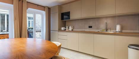 A modern kitchen with a round dining table, built-in appliances, and a view to the outside.