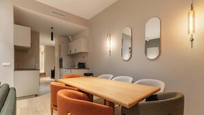 A modern dining area with a wooden table and four chairs, a kitchen in the background, and wall-mounted mirrors. - Élégant 3 pièces climatisé au cœur de Paris 10 (Paris)