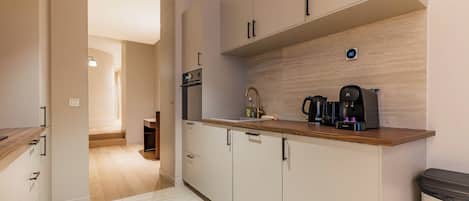 A modern kitchen with a wooden countertop, built-in appliances, and a view into the adjacent living area.