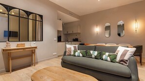 A modern living room with a sofa, a wooden bench, a console table, and a large mirror. - Élégant 3 pièces climatisé au cœur de Paris 10 (Paris)