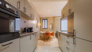 A modern kitchen with a dining area, featuring light wood cabinetry, a central island, and a view of the living room. - Élégant 3 pièces climatisé au cœur de Paris 10 (Paris)
