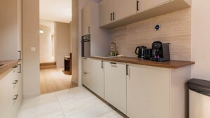 A modern kitchen with light wood cabinets, a built-in oven, and a coffee maker on the countertop. - Élégant 3 pièces climatisé au cœur de Paris 10 (Paris)