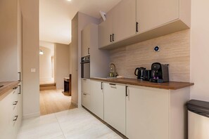 Eine moderne Küche mit hellen Holzschränken, einem eingebauten Ofen und einer Kaffeemaschine auf der Arbeitsfläche.