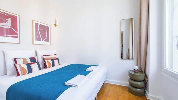 Une chambre d’hôtel bien aménagée, avec un grand lit, une table de chevet et une fenêtre avec des rideaux.