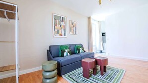 Un salon moderne avec un canapé gris, des coussins verts, un tapis à rayures et un plancher en bois.