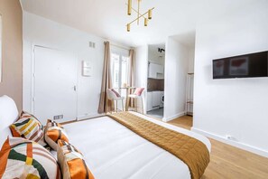 Una camera d'hotel moderna con un letto grande, una TV a parete e un angolo cottura sullo sfondo.