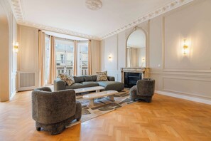 Ein geräumiges Wohnzimmer mit einer großen Couch, zwei Sesseln, einem Couchtisch und einem Kamin.