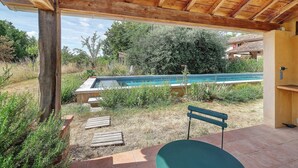 Ein überdachter Außenbereich mit Pool, Holzdeck und einer Bank.