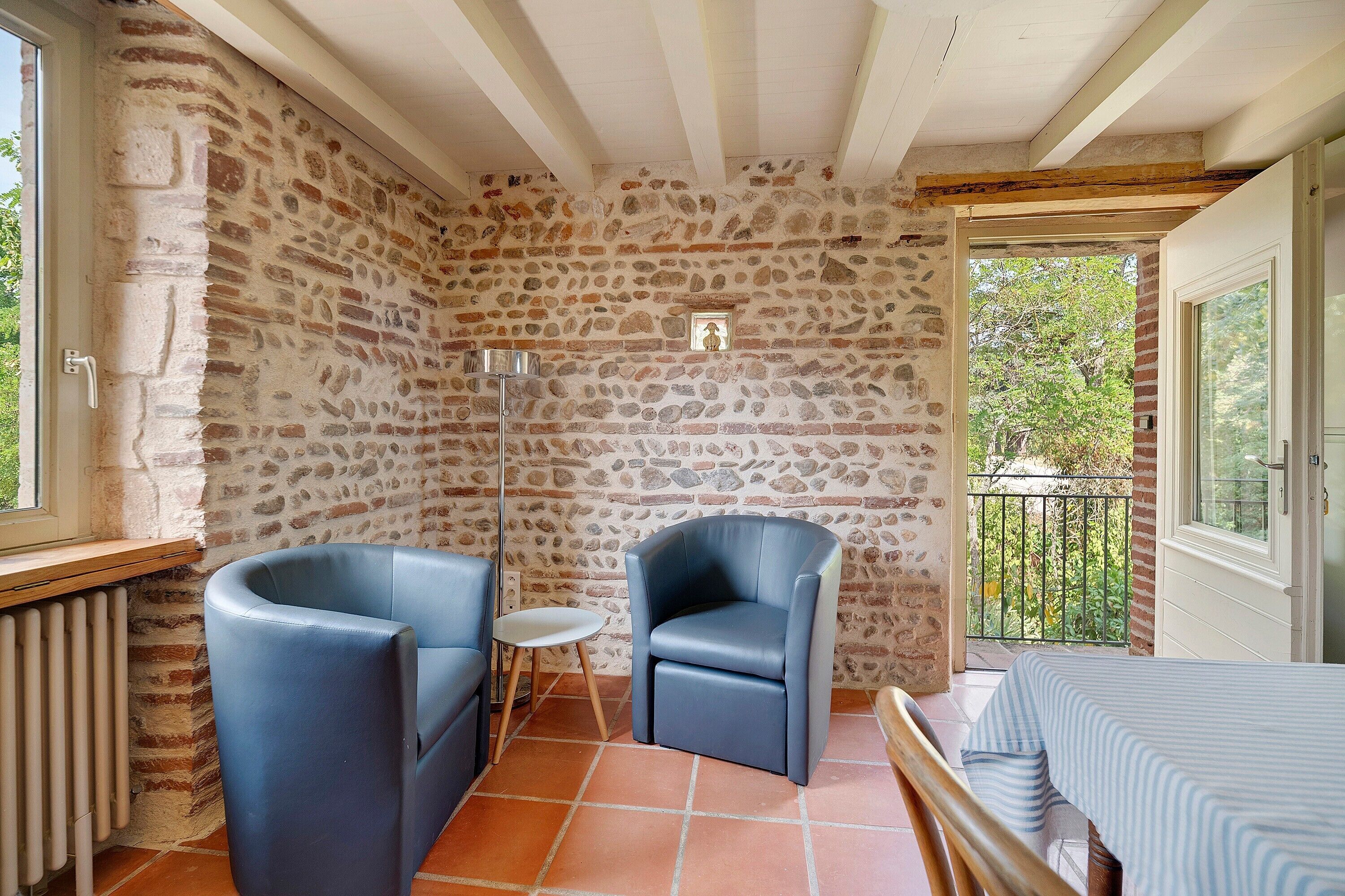 Una habitación con paredes de piedra, un balcón, una mesa y dos sillas.